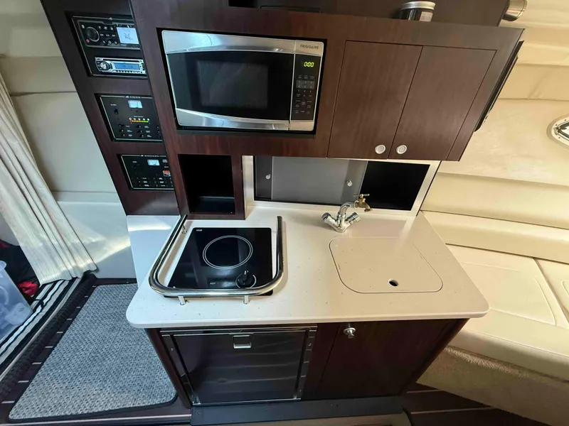 Slide: The Image of Compact kitchen area in a 2013 Monterey 280 SCR boat with microwave and stovetop. - 9