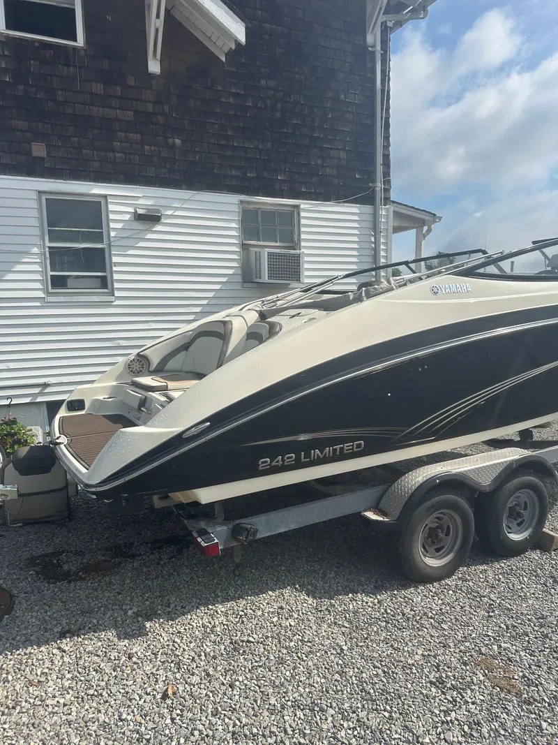 Slide: The Image of 2015 Yamaha Boats 242 Limited on trailer, parked beside a house. - 3