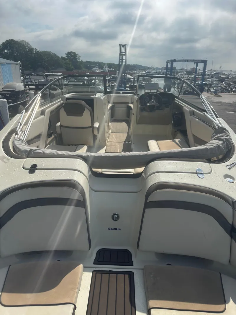 Slide: The Image of 2015 Yamaha Boats 242 Limited interior view at marina, showcasing seating and controls. - 6