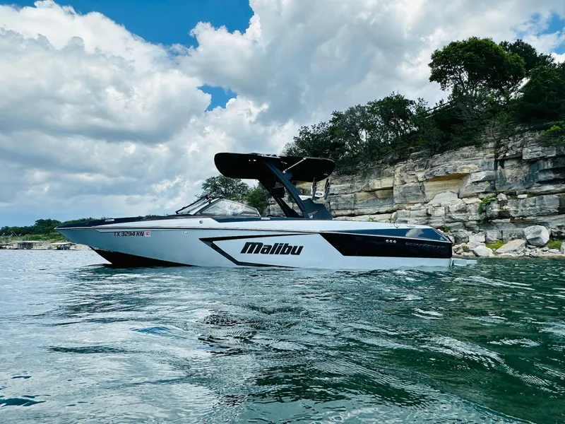 Slide: The Image of 2022 Malibu Wakesetter 24 MXZ boat on a scenic lake with rocky shoreline. - 3