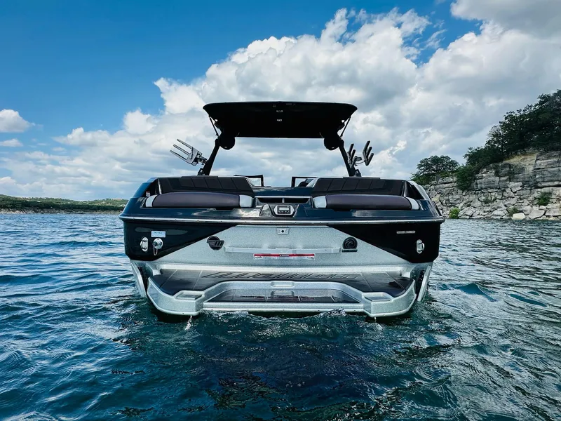 Slide: The Image of 2022 Malibu Wakesetter 24 MXZ on a scenic lake with rocky shoreline. - 6