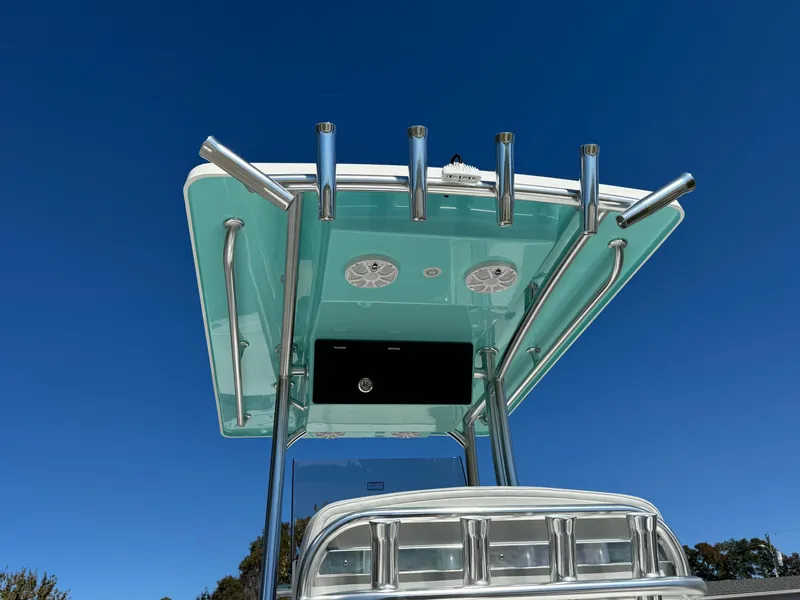 Slide: The Image of Bay Rider 2260 Skiff 2025 boat with T-top and rod holders against clear blue sky. - 3