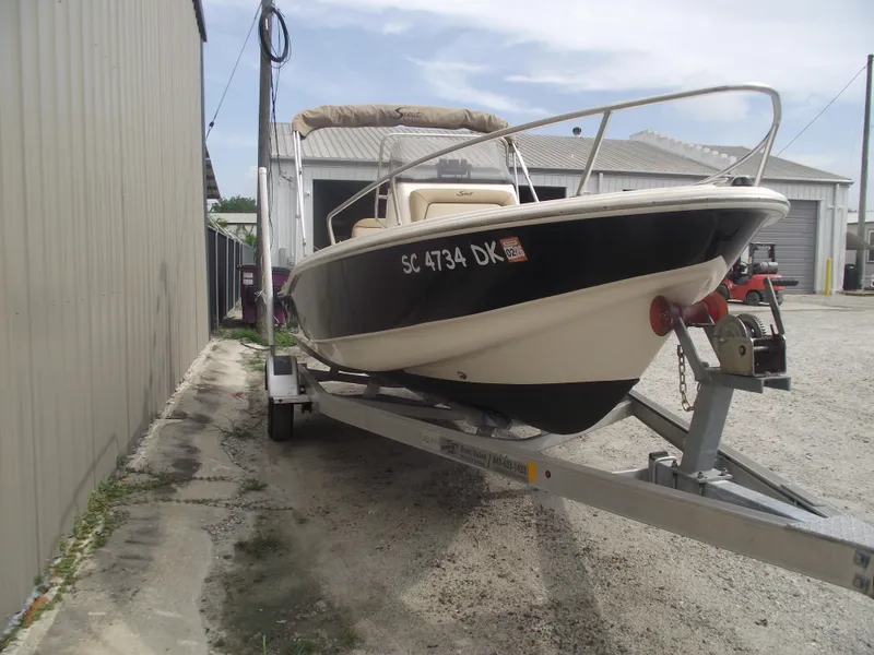 Slide: The Image of 2018 Scout 175 Sportfish boat on trailer near metal building. - 2
