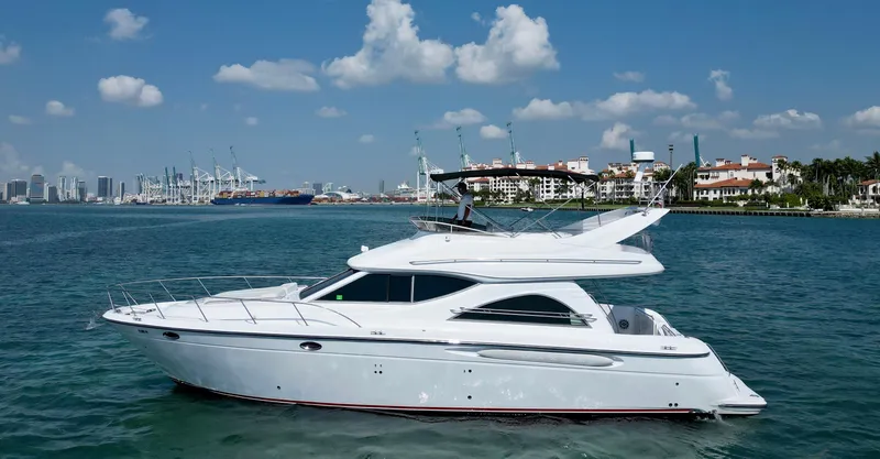 Slide: The Image of 1999 Maxum 4600 SCB yacht cruising on a sunny day near a city skyline. - 0