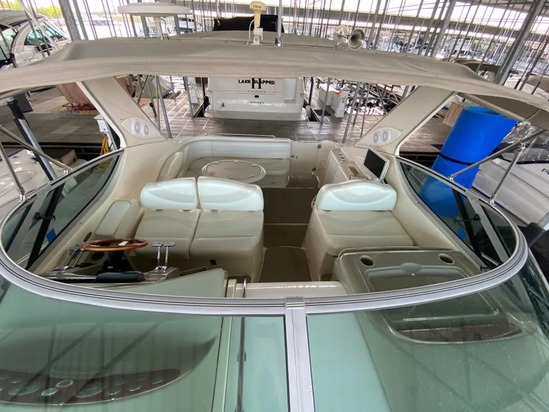 Slide: The Image of 1998 Maxum 3700 SCR boat interior with white seating and steering wheel in a marina. - 22