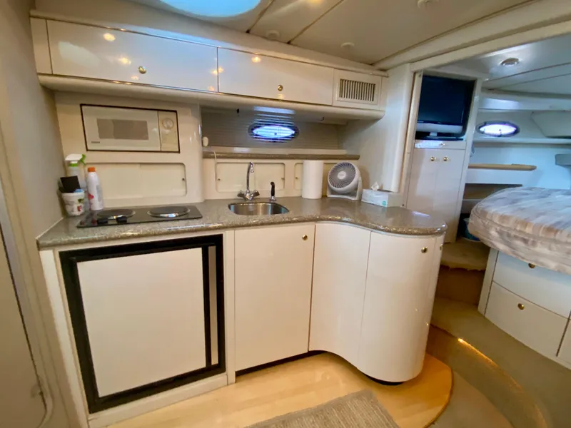 Slide: The Image of 1998 Maxum 3700 SCR yacht interior with kitchenette, featuring sink, stove, and microwave. - 27