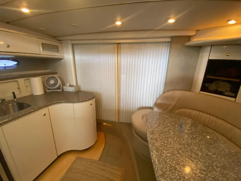 Slide: The Image of 1998 Maxum 3700 SCR yacht interior with kitchenette and seating area, featuring modern design and lighting. - 33