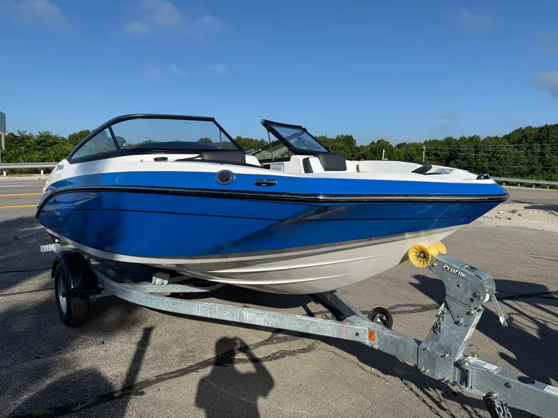 Slide: The Image of 2025 Yamaha Boats SX195 on trailer, blue and white design, parked outdoors. - 2