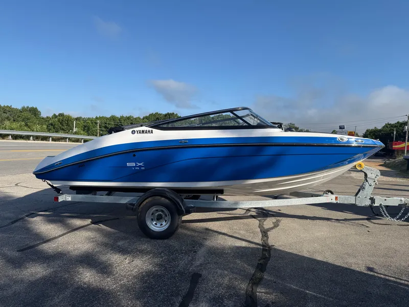 Slide: The Image of 2025 Yamaha SX195 boat on trailer, blue and white design, parked outdoors. - 4
