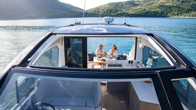 Slide: The Image of 2025 NX Boats NX50 Invictus HT cruising on serene waters with passengers enjoying a meal. - 21