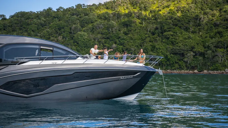 Slide: The Image of 2025 NX Boats NX50 Invictus HT cruising on serene waters near lush green landscape. - 28