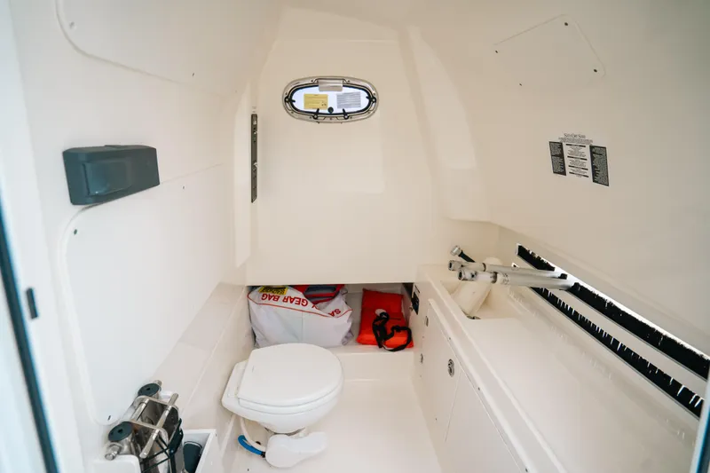 Slide: The Image of 2019 Boston Whaler 330 Outrage cabin interior with toilet and storage space. - 10