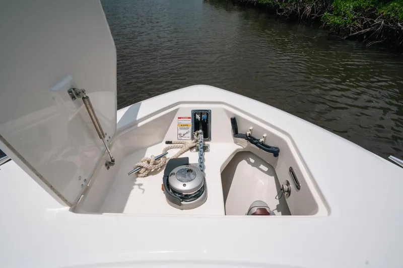 Slide: The Image of 2019 Boston Whaler 330 Outrage anchor compartment with rope and winch, open on calm water. - 11
