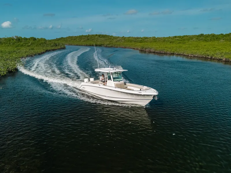 Slide: The Image of 2019 Boston Whaler 330 Outrage cruising on a scenic waterway under a clear blue sky. - 21