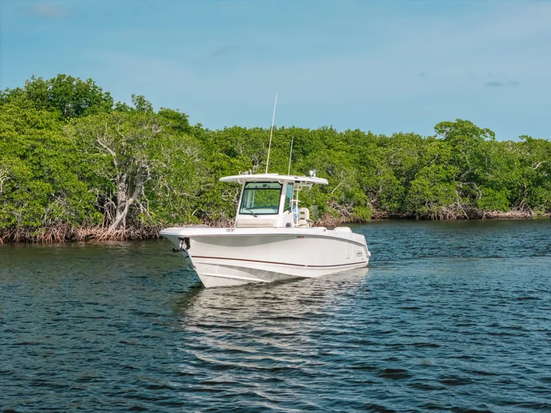 Slide: The Image of 2019 Boston Whaler 330 Outrage boat cruising on a calm river with lush green trees. - 22