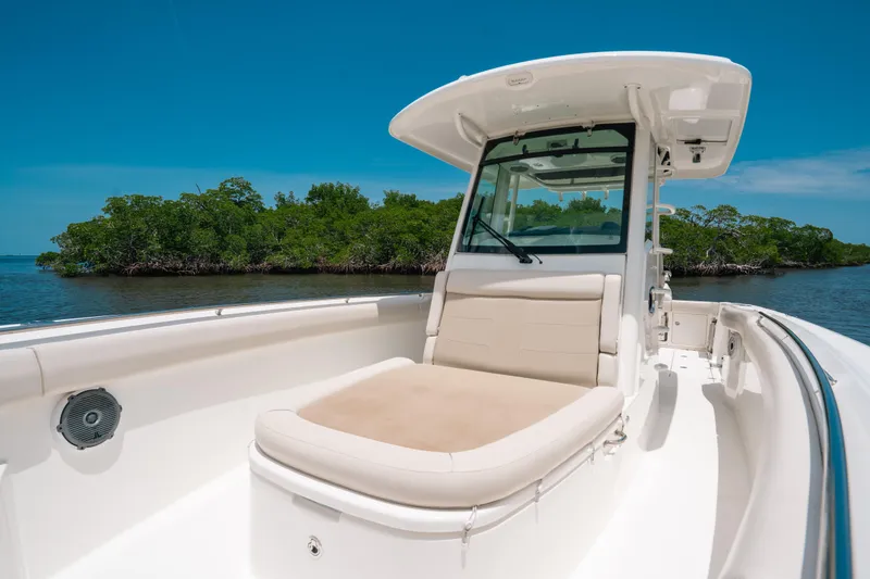 Slide: The Image of 2019 Boston Whaler 330 Outrage boat with cushioned seating, near lush green island. - 7