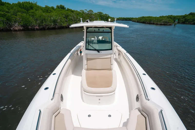 Slide: The Image of 2019 Boston Whaler 330 Outrage boat cruising on a calm river with lush greenery. - 8