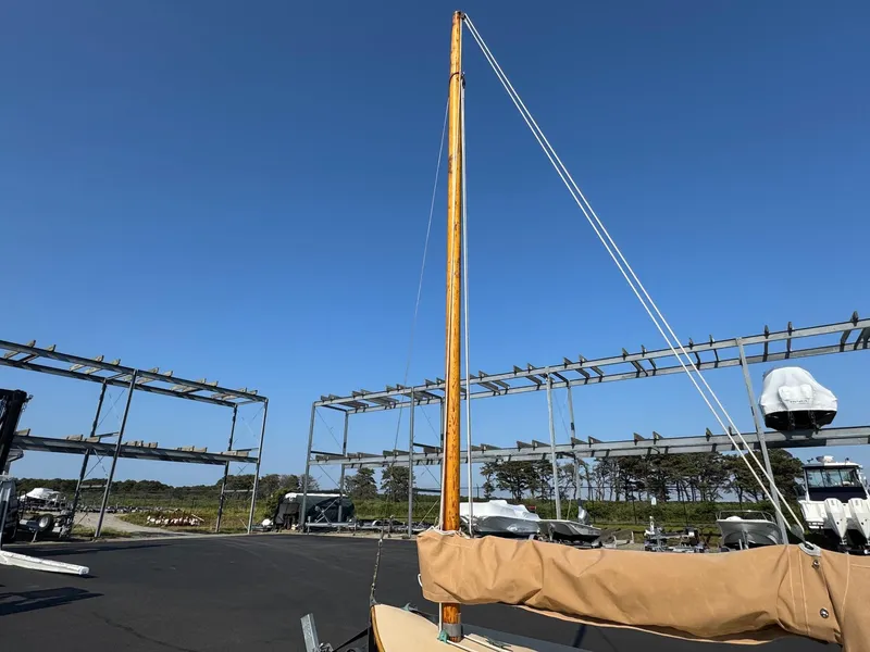 Slide: The Image of Custom 2004 Barnstable Cat Boat with mast, docked under clear blue sky. - 8