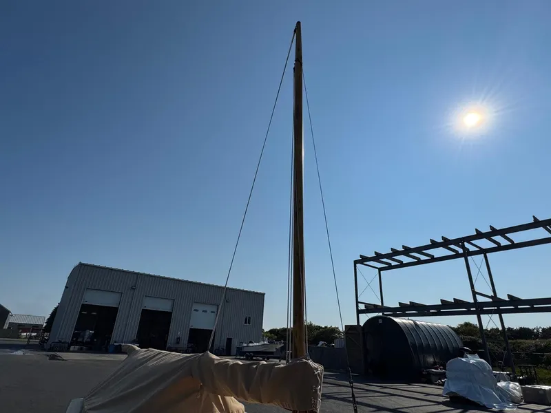 Slide: The Image of 2004 Custom Barnstable Cat Boat with mast, docked under clear blue sky. - 9