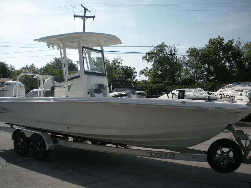 Slide: The Image of 2026 Robalo R246 Caymann boat on trailer, parked outdoors, side view. - 2