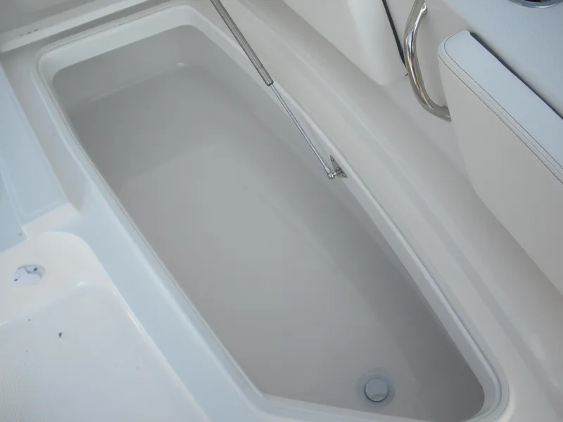 Slide: The Image of 2026 Robalo R246 Caymann boat storage compartment, white interior, stainless steel handle. - 8
