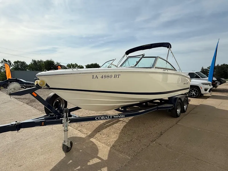 Slide: The Image of 2015 Cobalt 220 boat on trailer, parked outdoors, with visible registration number. - 2