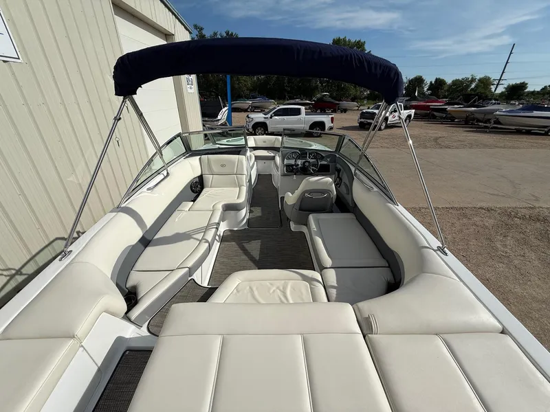 Slide: The Image of 2015 Cobalt 220 boat with white seating and blue canopy in a parking area. - 9