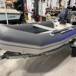 The Image of 2022 West Marine Compact Rib-310 inflatable boat on Load Rite trailer in a garage. - 1