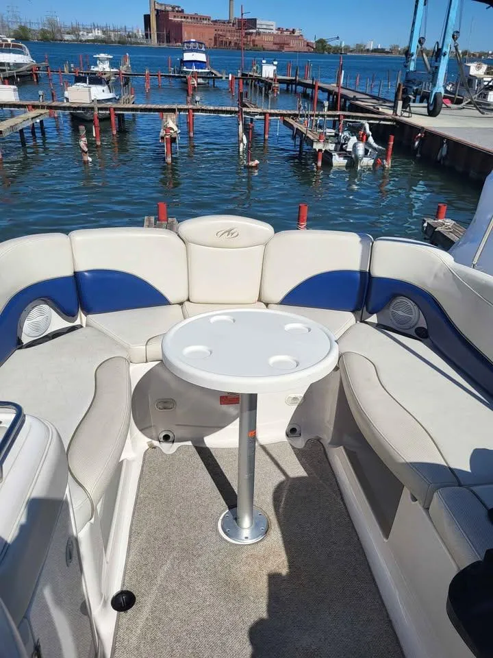 Slide: The Image of 2005 Monterey 263 ES Explorer boat interior with seating and table, docked at marina. - 6