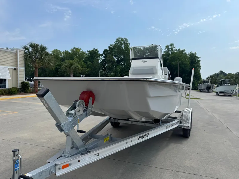Slide: The Image of 2025 Bay Rider 2060 Skiff on trailer, parked outdoors near trees and buildings. - 2