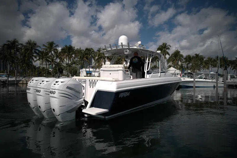 Slide: The Image of 2002 Intrepid 377 Walkaround Cuddy boat with triple outboard engines docked in marina. - 14