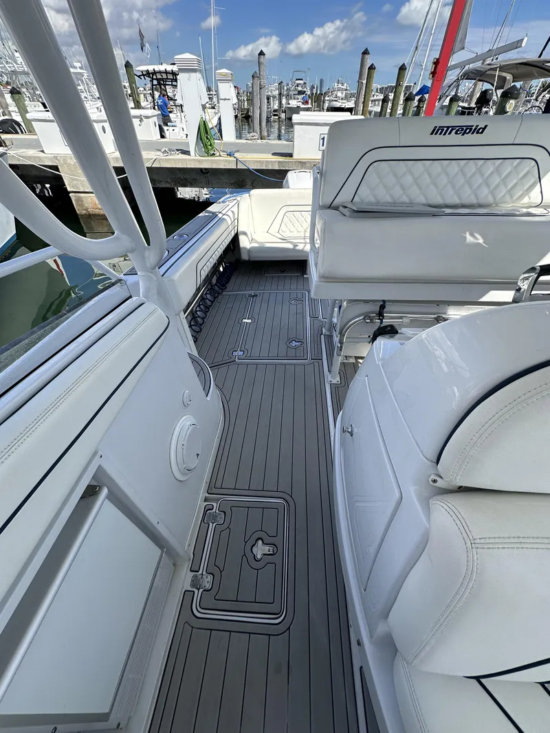 Slide: The Image of 2002 Intrepid 377 Walkaround Cuddy boat interior with white seating and gray flooring. - 44