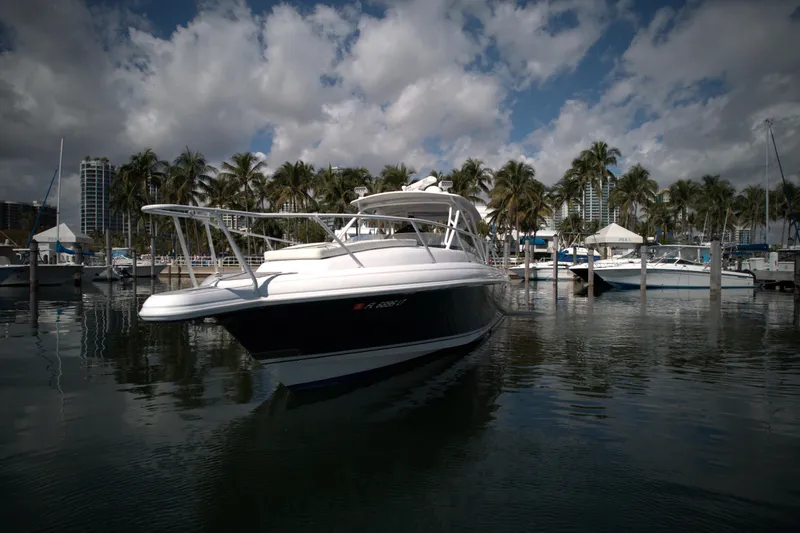 Slide: The Image of 2002 Intrepid 377 Walkaround Cuddy boat docked in a marina with palm trees. - 5