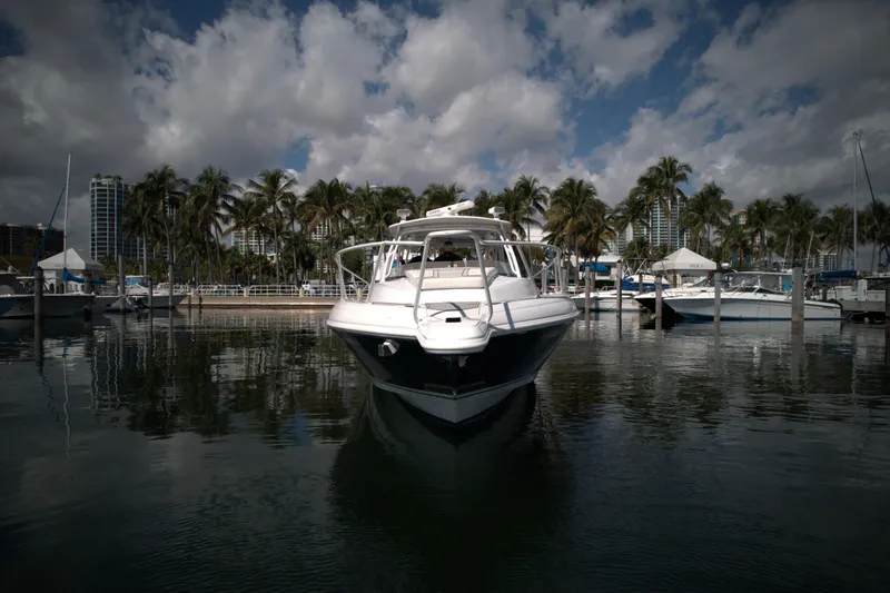 Slide: The Image of 2002 Intrepid 377 Walkaround Cuddy boat docked in a marina with palm trees. - 6