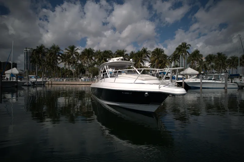 Slide: The Image of 2002 Intrepid 377 Walkaround Cuddy boat docked in a marina with palm trees. - 7