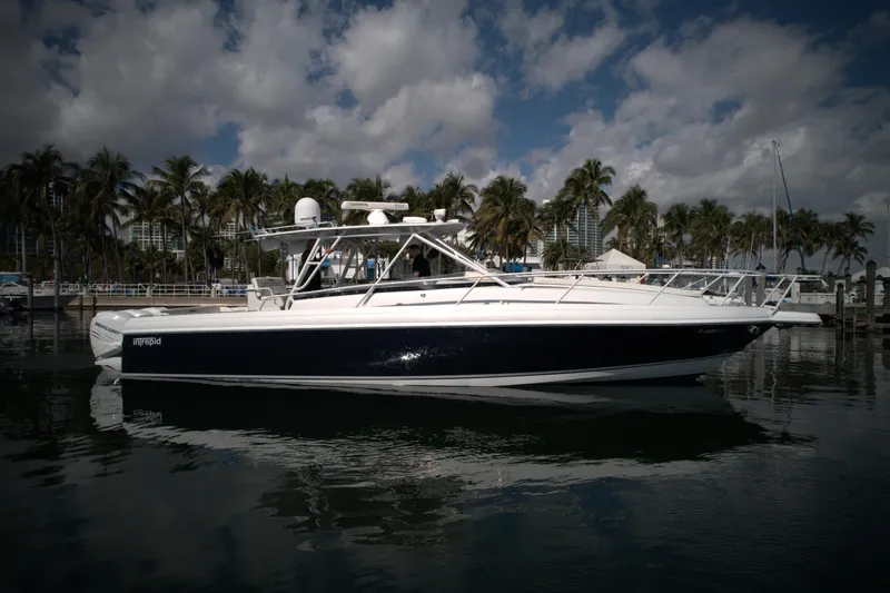 Slide: The Image of 2002 Intrepid 377 Walkaround Cuddy boat docked in a marina with palm trees. - 9