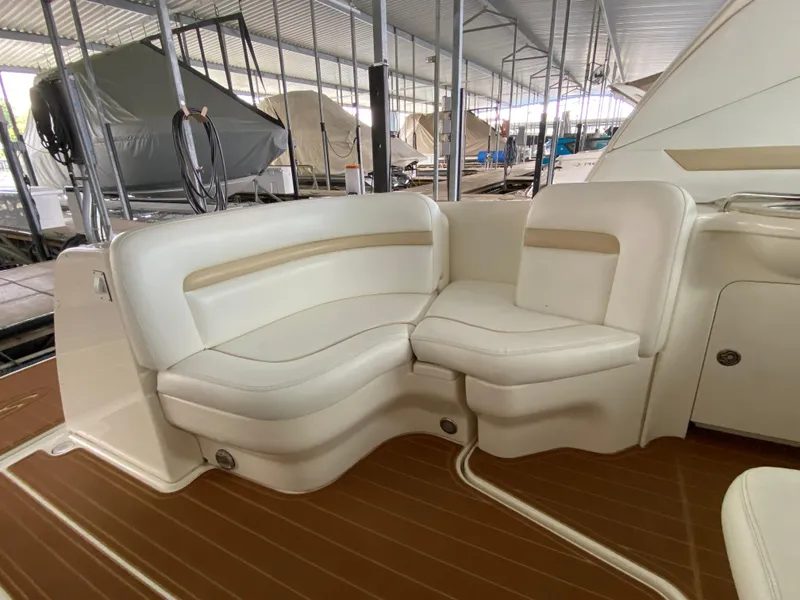 Slide: The Image of 2008 Sea Ray 38 Sundancer boat interior with white seating and wood flooring in a covered dock. - 12