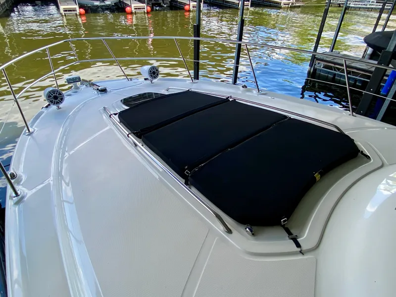 Slide: The Image of 2008 Sea Ray 38 Sundancer boat deck with black sun pads, docked by the water. - 7