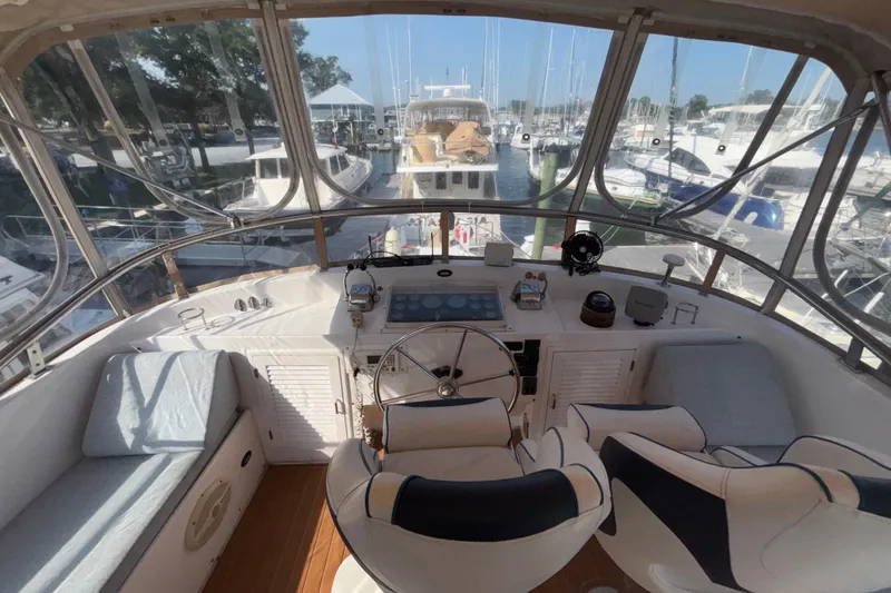 Slide: The Image of 1989 Jefferson 42 Sundeck Motor Yacht helm with marina view, featuring dual seats and navigation controls. - 25
