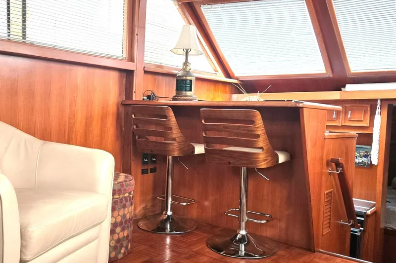 Slide: The Image of 1989 Jefferson 42 Sundeck Motor Yacht interior with wooden bar, stools, and cozy seating. - 5