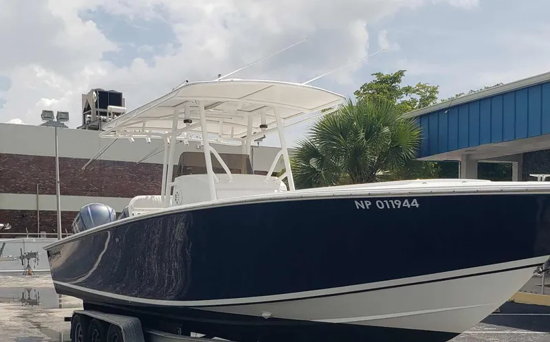 Slide: The Image of 2003 Jupiter 31 Center Console boat on trailer, parked outdoors under cloudy sky. - 1