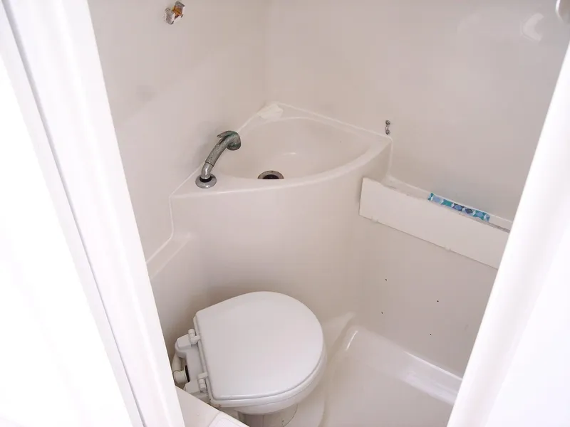 Slide: The Image of Compact bathroom in 2003 Jupiter 31 Center Console boat, featuring toilet and sink. - 14