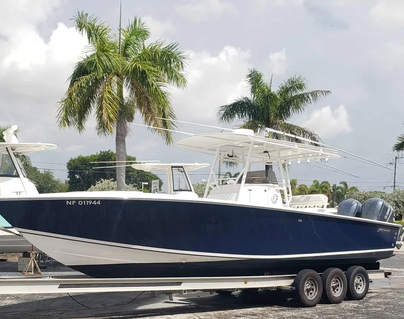 Slide: The Image of 2003 Jupiter 31 Center Console boat on trailer, parked near palm trees. - 3