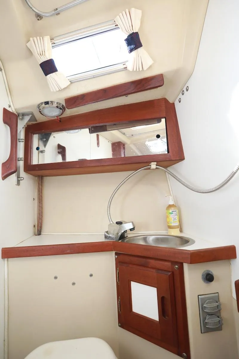 Slide: The Image of Interior of 1985 Catalina 30 sailboat bathroom with sink, mirror, and wooden cabinetry. - 13