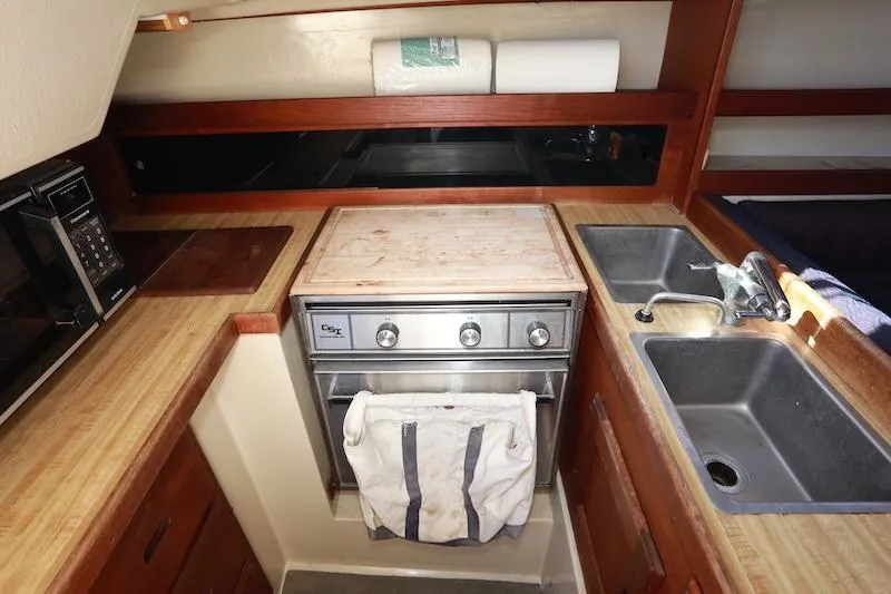 Slide: The Image of Compact kitchen in a 1985 Catalina 30 sailboat with stove, sink, and microwave. - 9