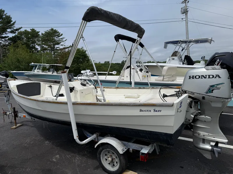 Slide: The Image of 2001 Bristol Skiff 17 boat with Honda outboard motor on trailer, parked outdoors. - 0