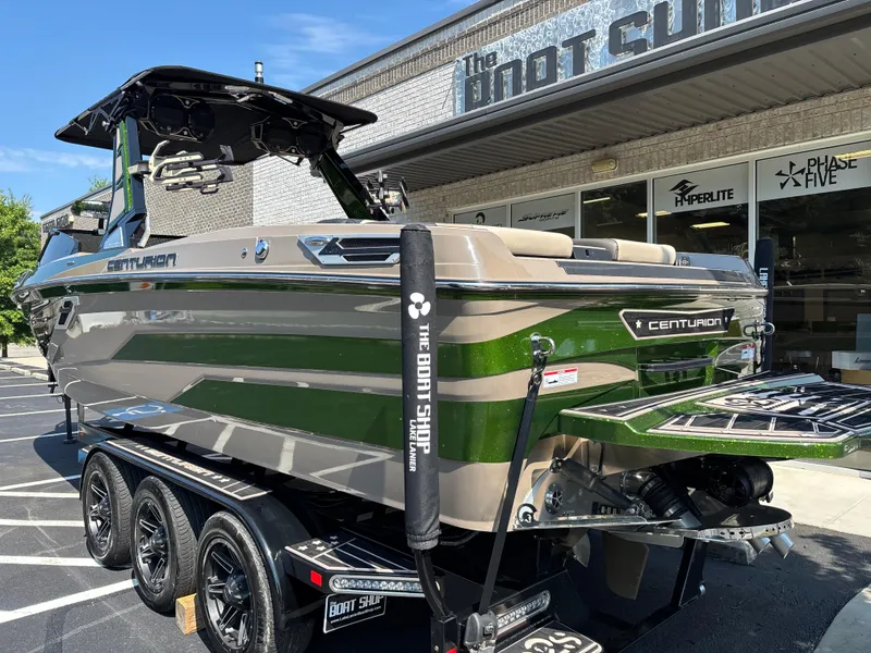 Slide: The Image of 2023 Centurion Ri265 boat with green and beige design at dealership. - 2