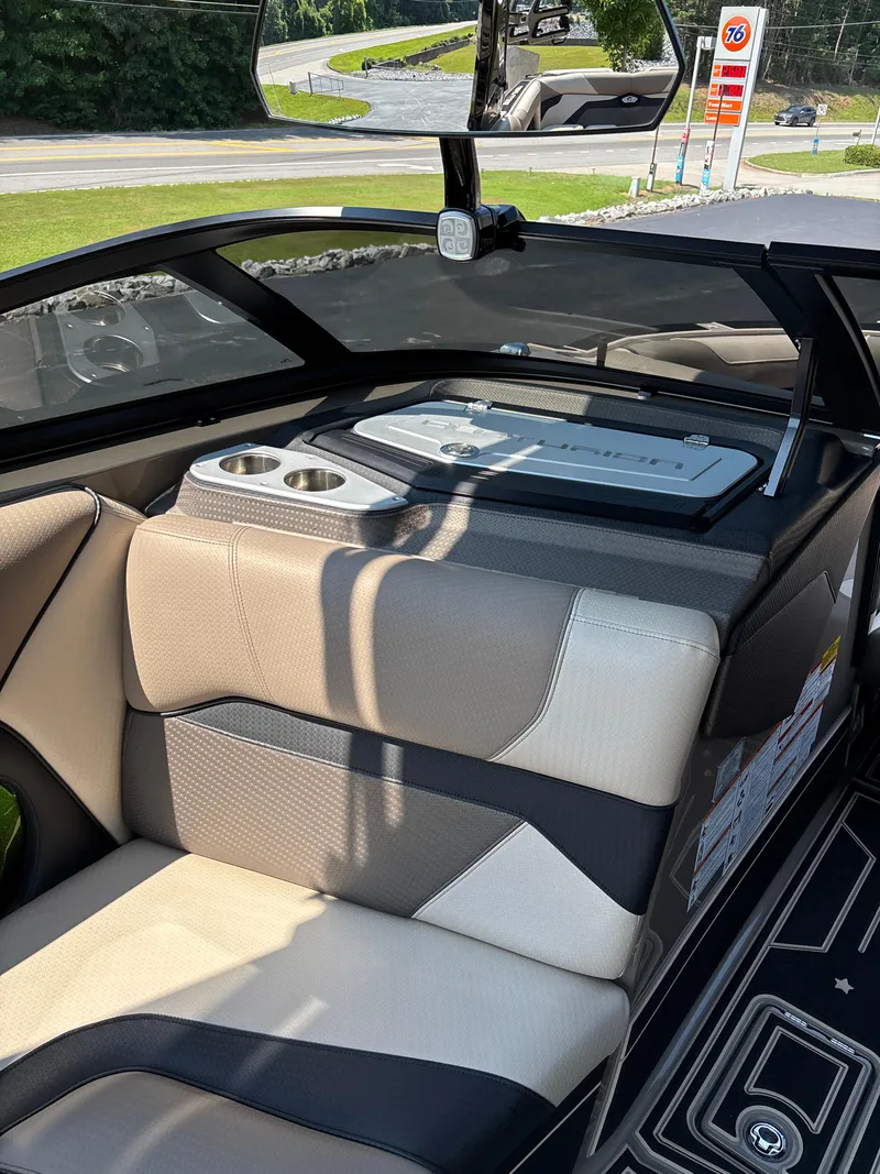 Slide: The Image of 2023 Centurion Ri265 boat interior with beige and black seating, cup holders, and rear view mirror. - 9