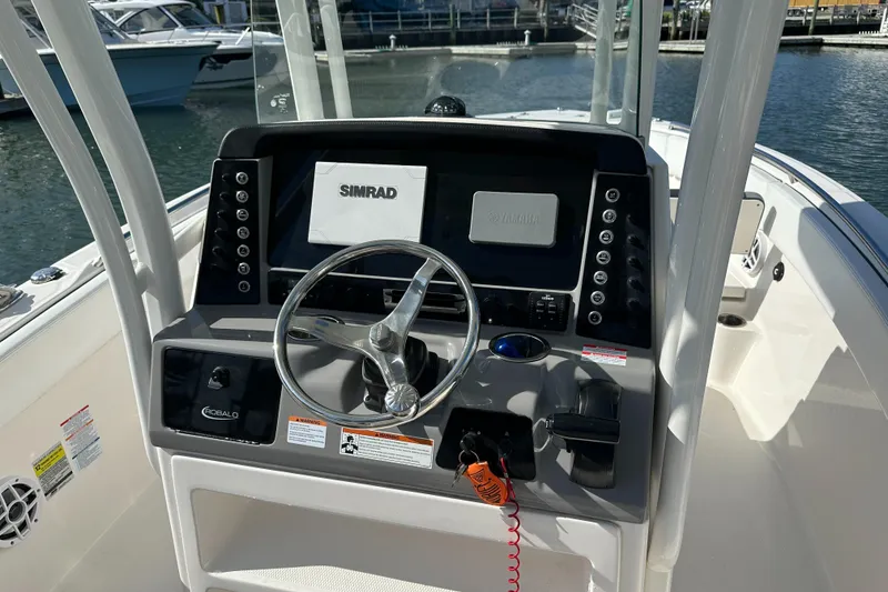 Slide: The Image of 2021 Robalo R230 Center Console boat dashboard with steering wheel and Simrad display. - 15