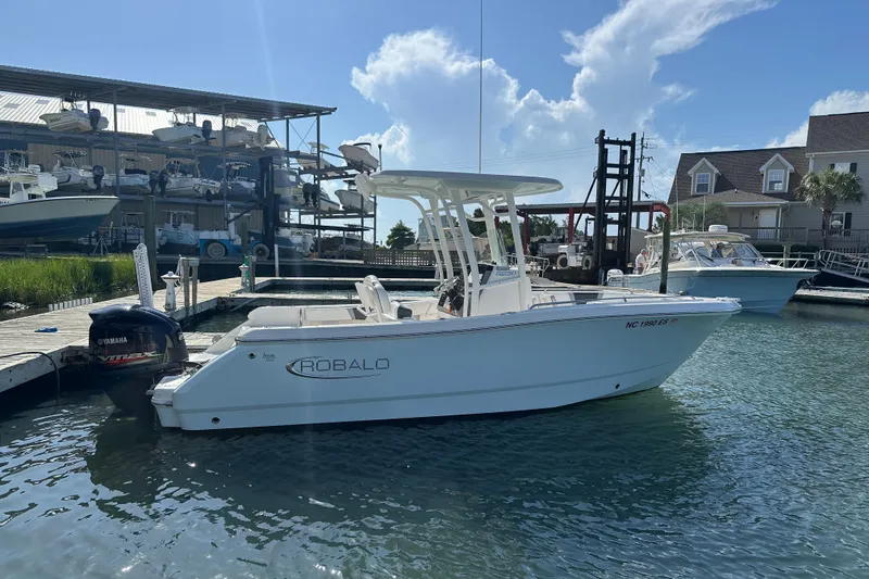 Slide: The Image of 2021 Robalo R230 Center Console boat docked at marina under clear blue sky. - 2